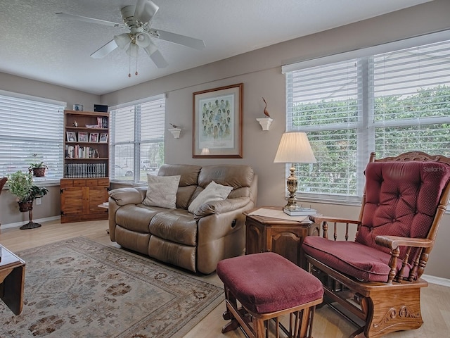 living room featuring light wood-style flooring, a textured ceiling, a ceiling fan, and a wealth of natural light