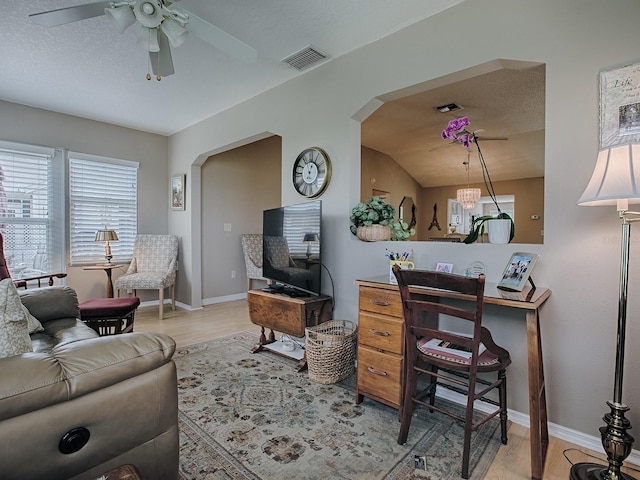 living room featuring arched walkways, light wood finished floors, visible vents, and baseboards