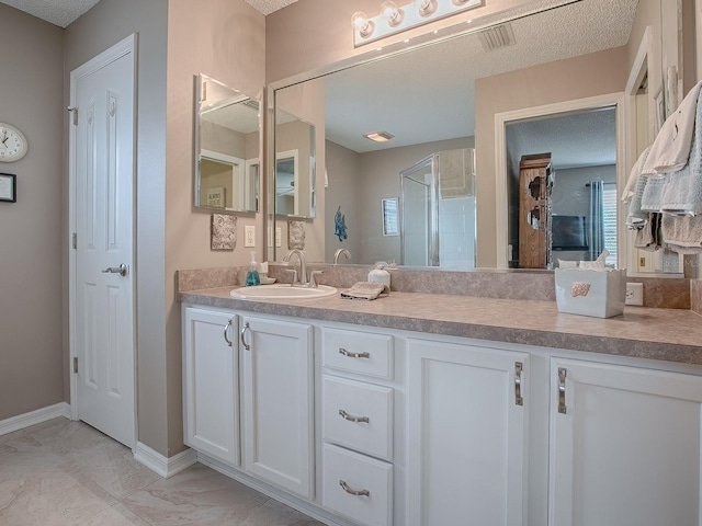 full bathroom with marble finish floor, vanity, baseboards, and a textured ceiling