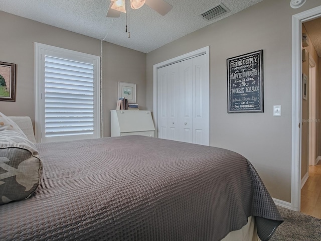bedroom with a closet, visible vents, ceiling fan, a textured ceiling, and baseboards