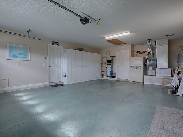 garage featuring visible vents, freestanding refrigerator, and a garage door opener