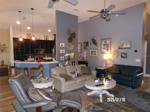 living room with light hardwood / wood-style floors, ceiling fan, and sink