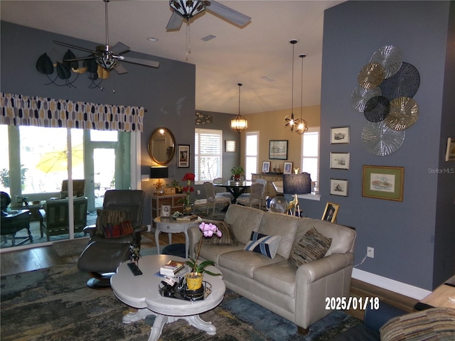 living room featuring ceiling fan with notable chandelier, a towering ceiling, and hardwood / wood-style floors