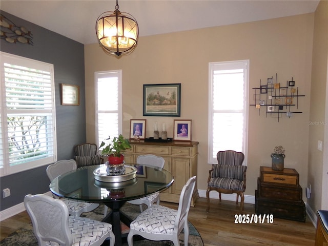 dining space with hardwood / wood-style floors and an inviting chandelier