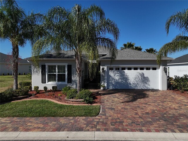10173 Julia Isles Ave, Oxford, FL 34484 - ranch-style home with stucco siding, decorative driveway, and a garage