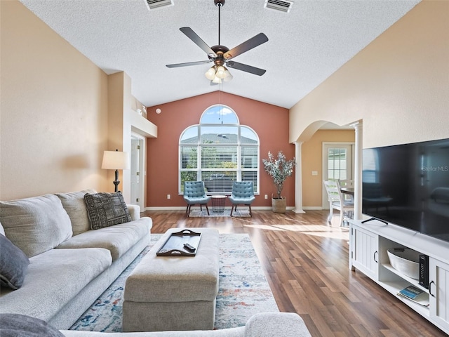 living room with dark wood-type flooring, vaulted ceiling, decorative columns, and a wealth of natural light