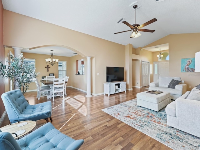 living room with lofted ceiling, hardwood / wood-style floors, ceiling fan with notable chandelier, and decorative columns