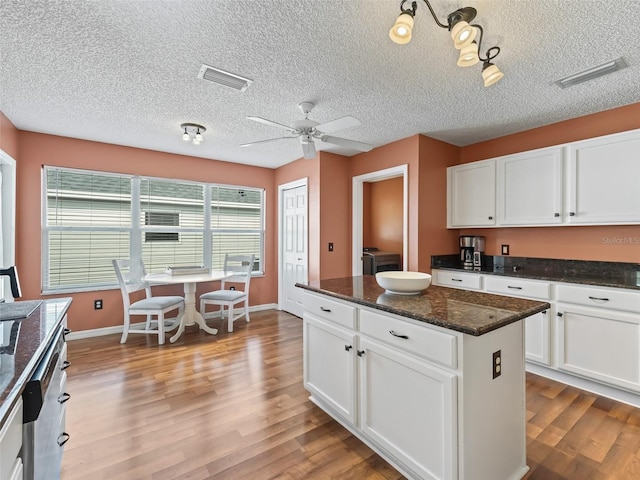 kitchen featuring a kitchen island, dark stone countertops, white cabinets, washer and clothes dryer, and light wood-type flooring