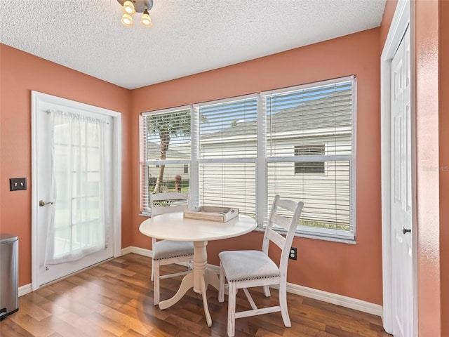 dining room with wood-type flooring and a textured ceiling