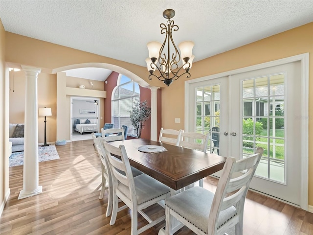 dining room with french doors, a healthy amount of sunlight, decorative columns, and light wood-type flooring