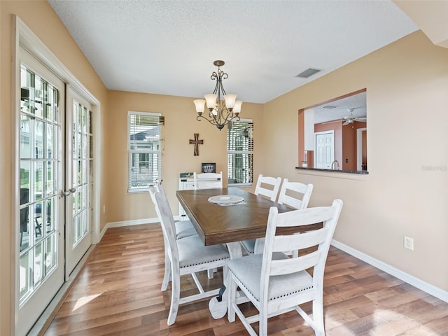 dining area featuring an inviting chandelier, a textured ceiling, and light wood-type flooring