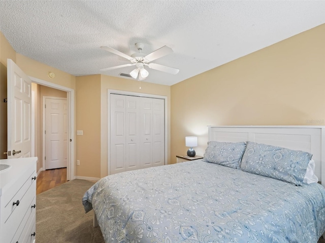 carpeted bedroom with a textured ceiling, ceiling fan, and a closet