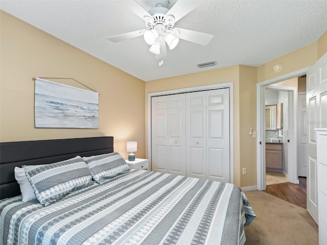 bedroom with a textured ceiling, a closet, ceiling fan, and carpet flooring