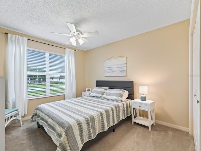 bedroom with ceiling fan, carpet floors, and a textured ceiling
