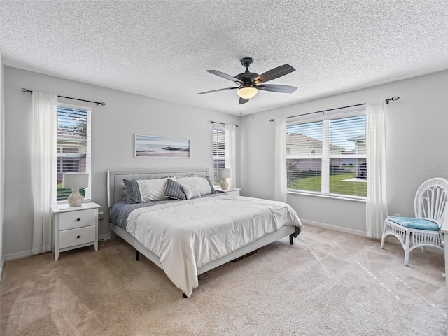 carpeted bedroom featuring multiple windows, ceiling fan, and a textured ceiling
