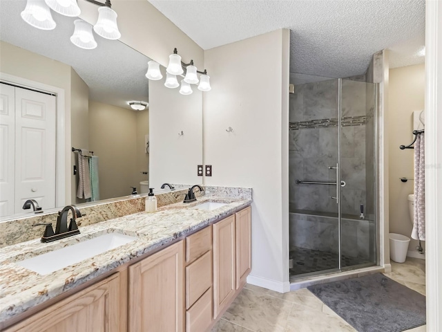 bathroom featuring vanity, a shower with shower door, toilet, and a textured ceiling