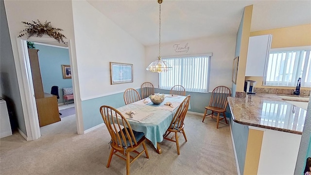 dining area with light carpet, sink, vaulted ceiling, and an inviting chandelier