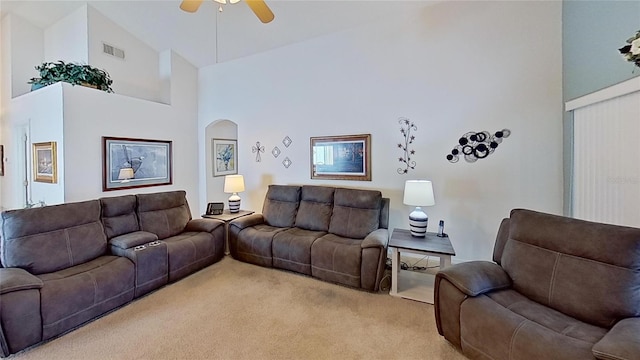 carpeted living room with ceiling fan and high vaulted ceiling