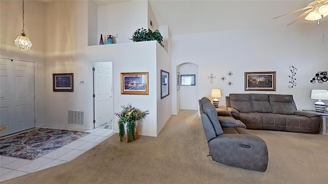 carpeted living room featuring a towering ceiling and ceiling fan