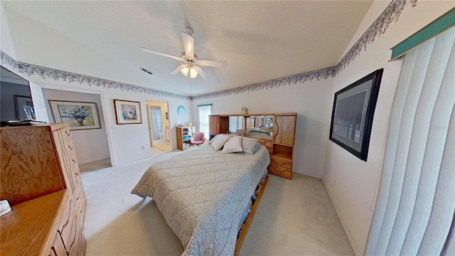 carpeted bedroom with a textured ceiling, ceiling fan, and ensuite bath