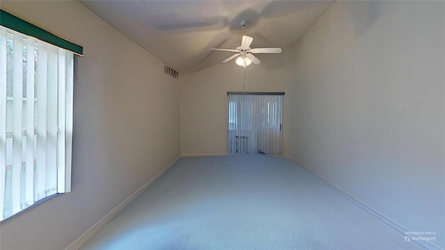 empty room with vaulted ceiling, ceiling fan, and carpet