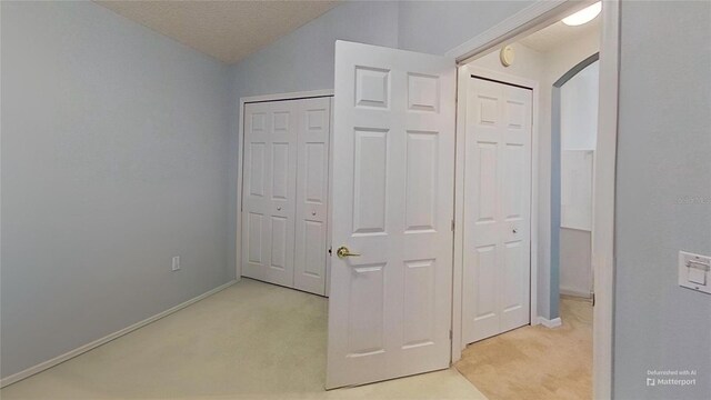 unfurnished bedroom featuring lofted ceiling and light colored carpet