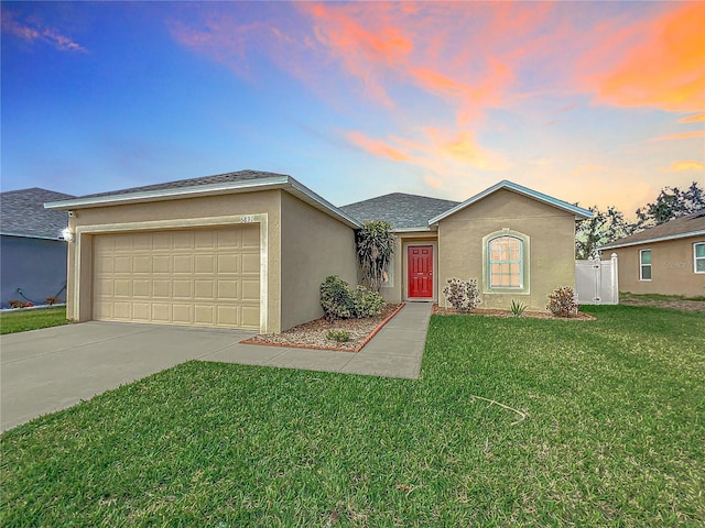 ranch-style home with a garage and a lawn