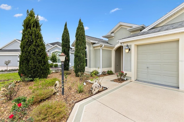 view of front of house featuring driveway, an attached garage, and stucco siding