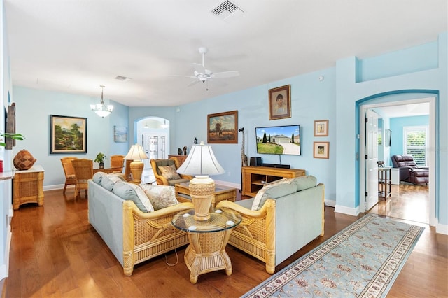 living room with arched walkways, wood finished floors, visible vents, and baseboards