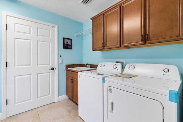 laundry area featuring light tile patterned flooring, a sink, visible vents, cabinet space, and washing machine and clothes dryer