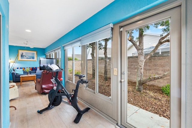 workout area featuring light wood-type flooring, a sunroom, and a ceiling fan