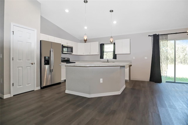 kitchen featuring pendant lighting, appliances with stainless steel finishes, white cabinets, a kitchen island, and vaulted ceiling