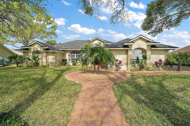 view of front of property with roof with shingles, a front lawn, and stucco siding