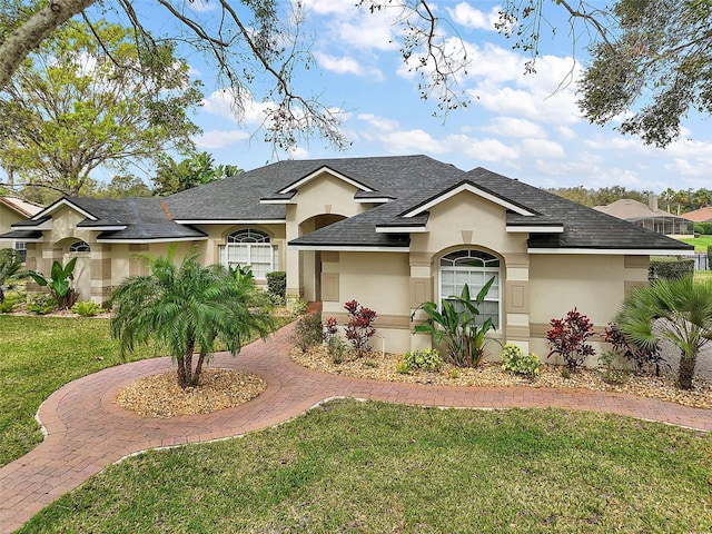 ranch-style home featuring roof with shingles, a front lawn, and stucco siding