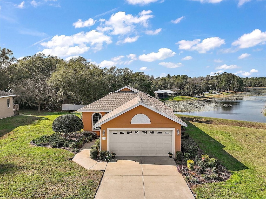 125 Twin Lake Cir, Umatilla, FL 32784 - view of front of property featuring a garage, a front lawn, and a water view