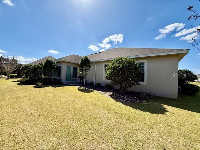 back of property featuring a lawn and stucco siding