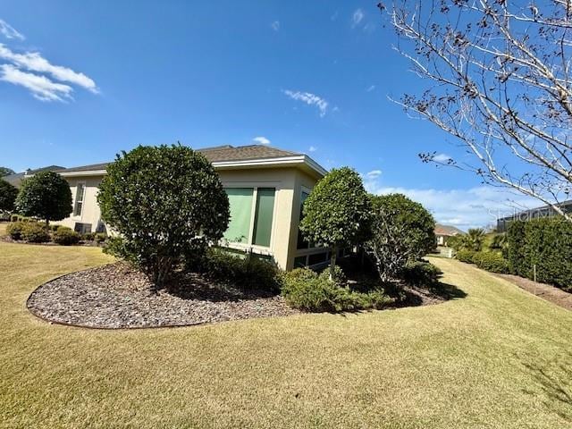 view of side of home with a yard and stucco siding