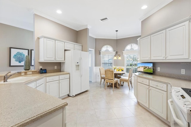 kitchen featuring light countertops, a sink, white cabinets, white appliances, and decorative light fixtures