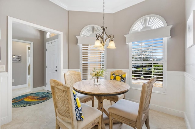 dining room featuring a notable chandelier, wainscoting, light tile patterned flooring, and crown molding