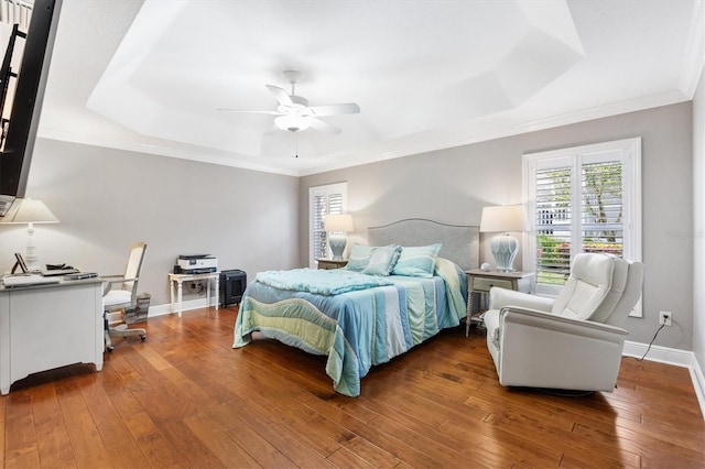 bedroom featuring baseboards, crown molding, a raised ceiling, and wood finished floors