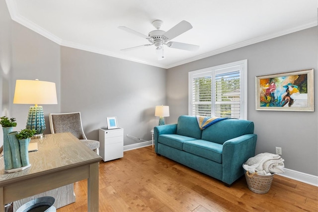 sitting room with a ceiling fan, light wood finished floors, baseboards, and crown molding