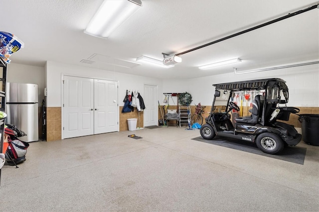 garage with freestanding refrigerator and a garage door opener