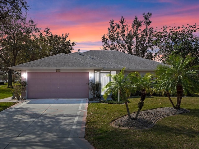 ranch-style house featuring a garage and a lawn