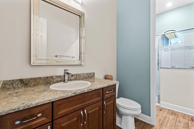 bathroom with toilet, wood-type flooring, an enclosed shower, and vanity