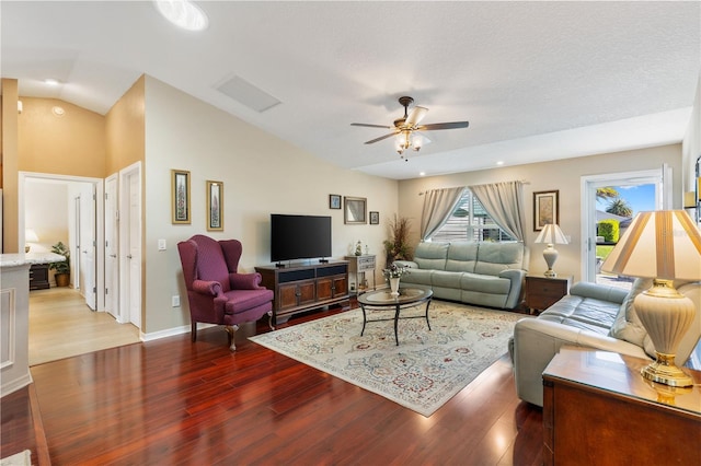 living room featuring lofted ceiling, visible vents, a ceiling fan, and wood finished floors