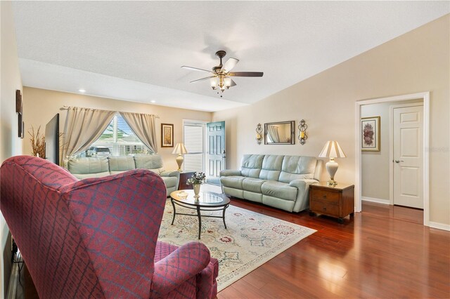 living area featuring dark wood-type flooring, vaulted ceiling, a textured ceiling, ceiling fan, and baseboards