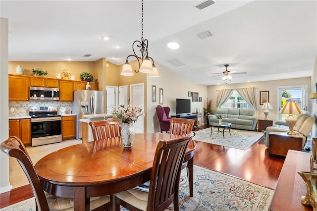 dining room with lofted ceiling, light wood finished floors, ceiling fan, and visible vents