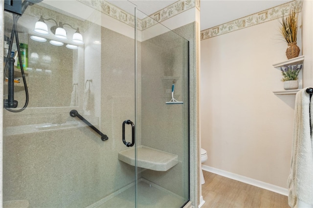 bathroom with wood finished floors, toilet, and a shower stall