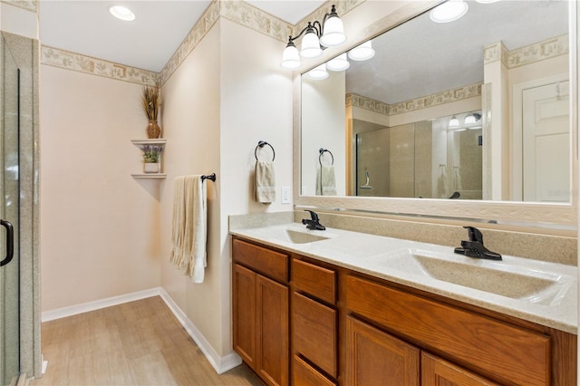 full bathroom featuring baseboards, double vanity, a sink, and a shower stall