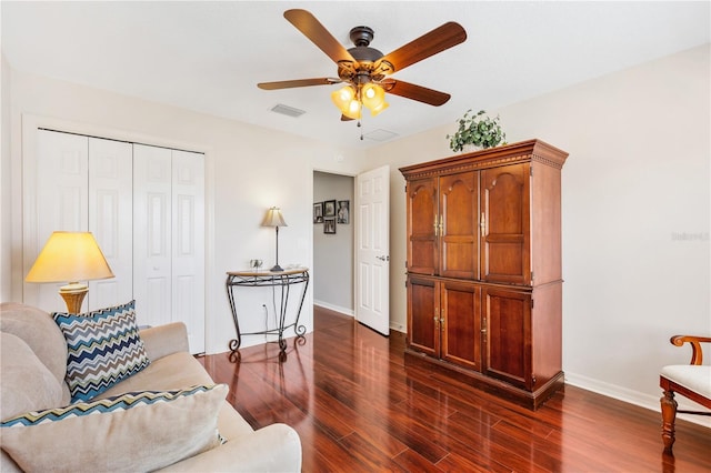 living room with a ceiling fan, dark wood-style flooring, visible vents, and baseboards